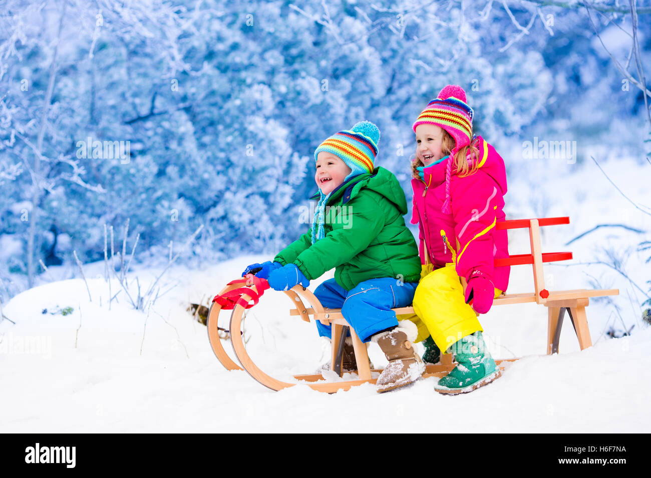 Infant Sleigh Riding Little girl and boy enjoy a sleigh ride. Child sledding. Toddler kid ...