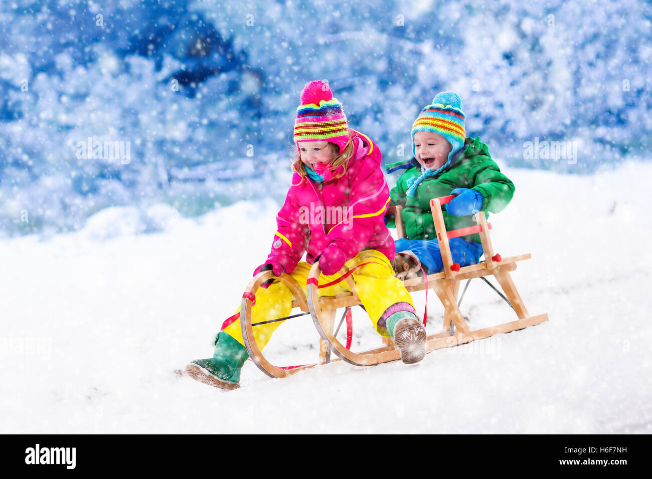Infant Sleigh Riding Little girl and boy enjoy a sleigh ride. Child sledding. Toddler kid ...