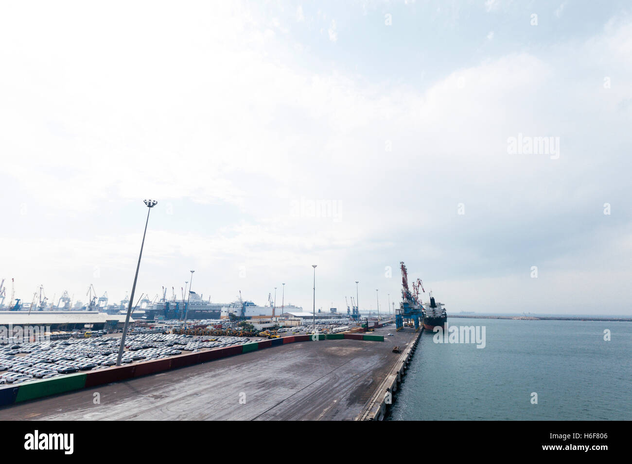 View of a commercial harbor with a docking ship and a huge car park