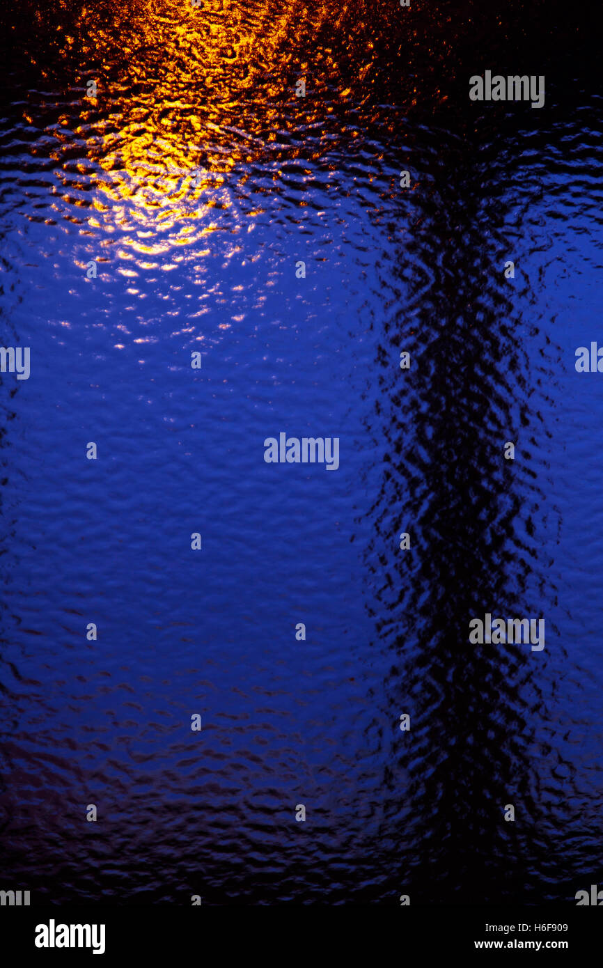 Abstract view of tungsten lighting reflecting off of textured glass