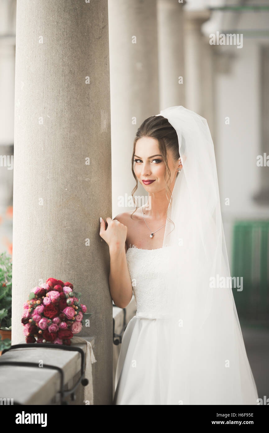 Beautiful bride with wedding bouquet posing in old city Stock Photo - Alamy