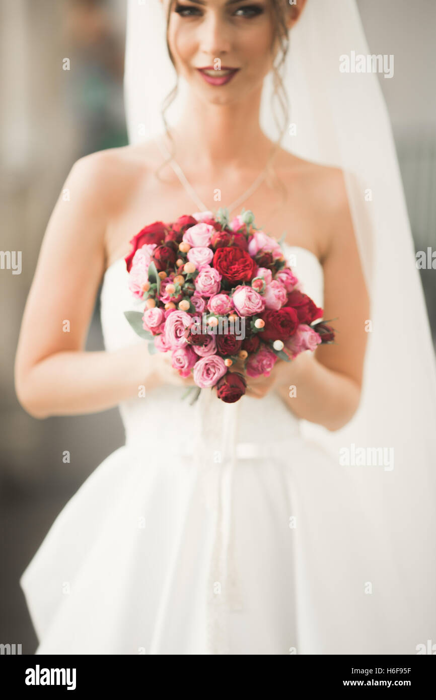 Beautiful bride with wedding bouquet posing in old city Stock Photo - Alamy