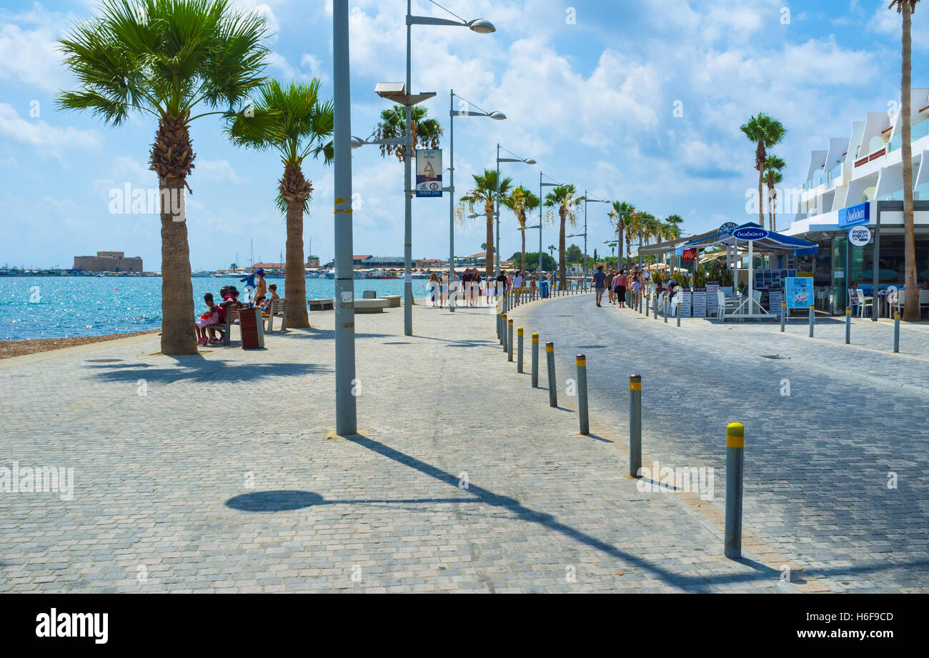 The busy promenade with many street cafes and bars and the medieval castle on the background, Paphos Stock Photo