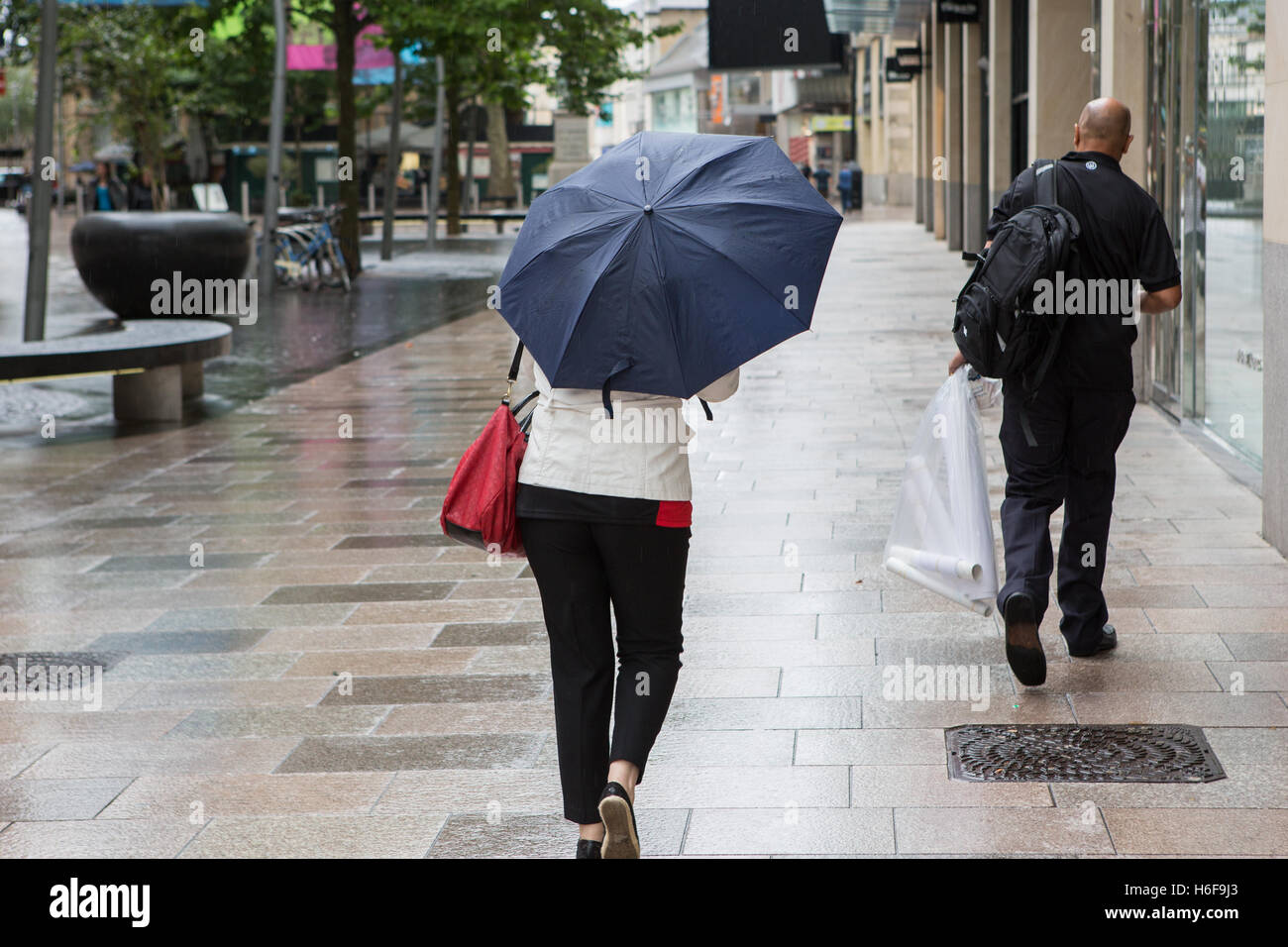 A woman with umbrella walking along a street in Cardiff Stock Photo - Alamy