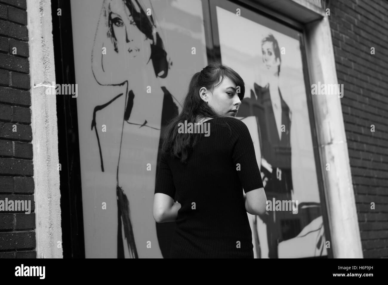 A young girl walking passed an illustrated shop window looking back at