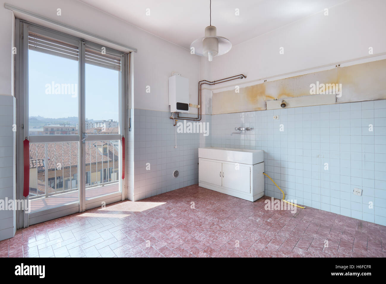 Old empty kitchen room with tiled floor and walls Stock Photo
