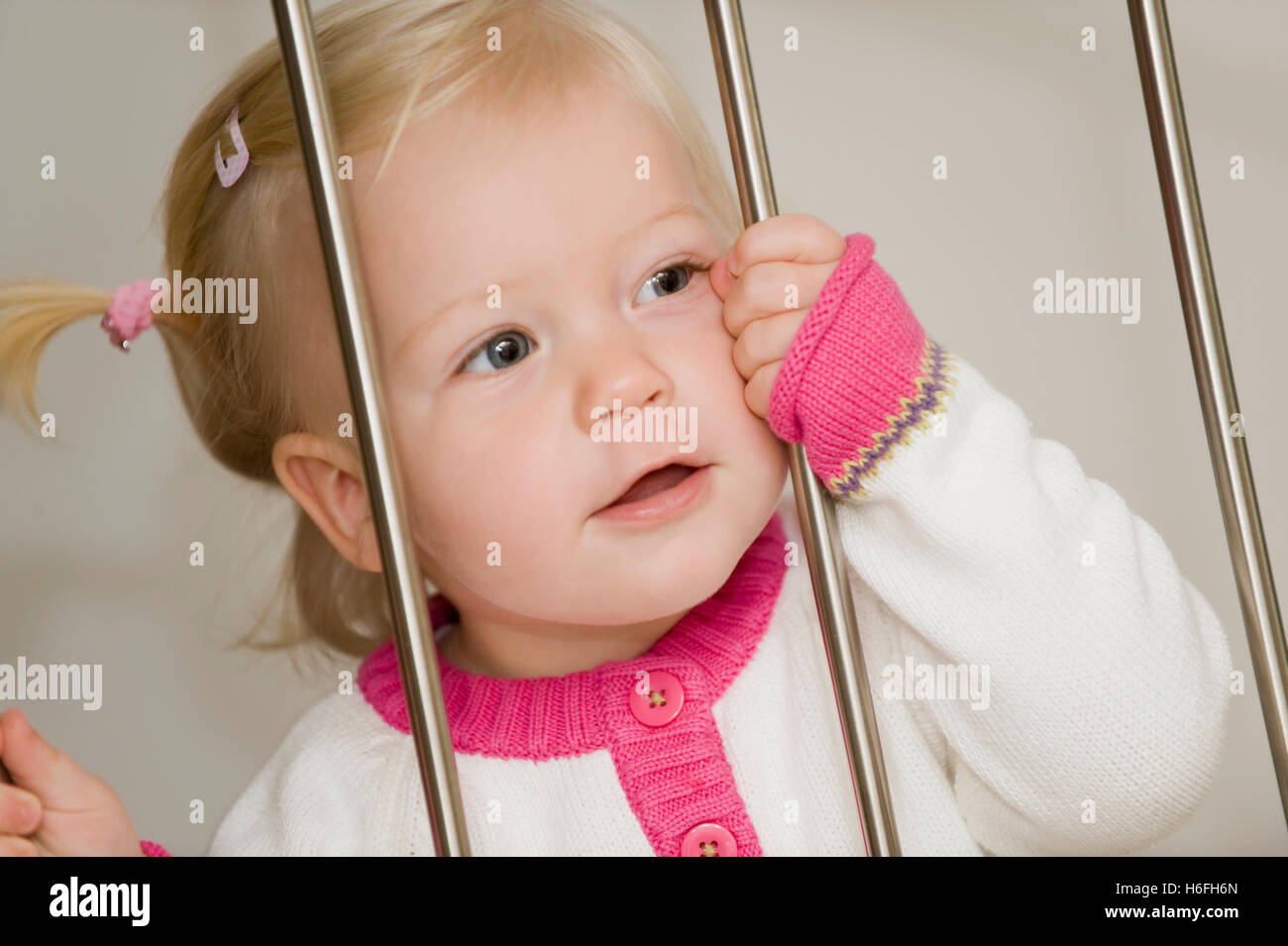 Blonde, 1-year old girl, behind bars Stock Photo
