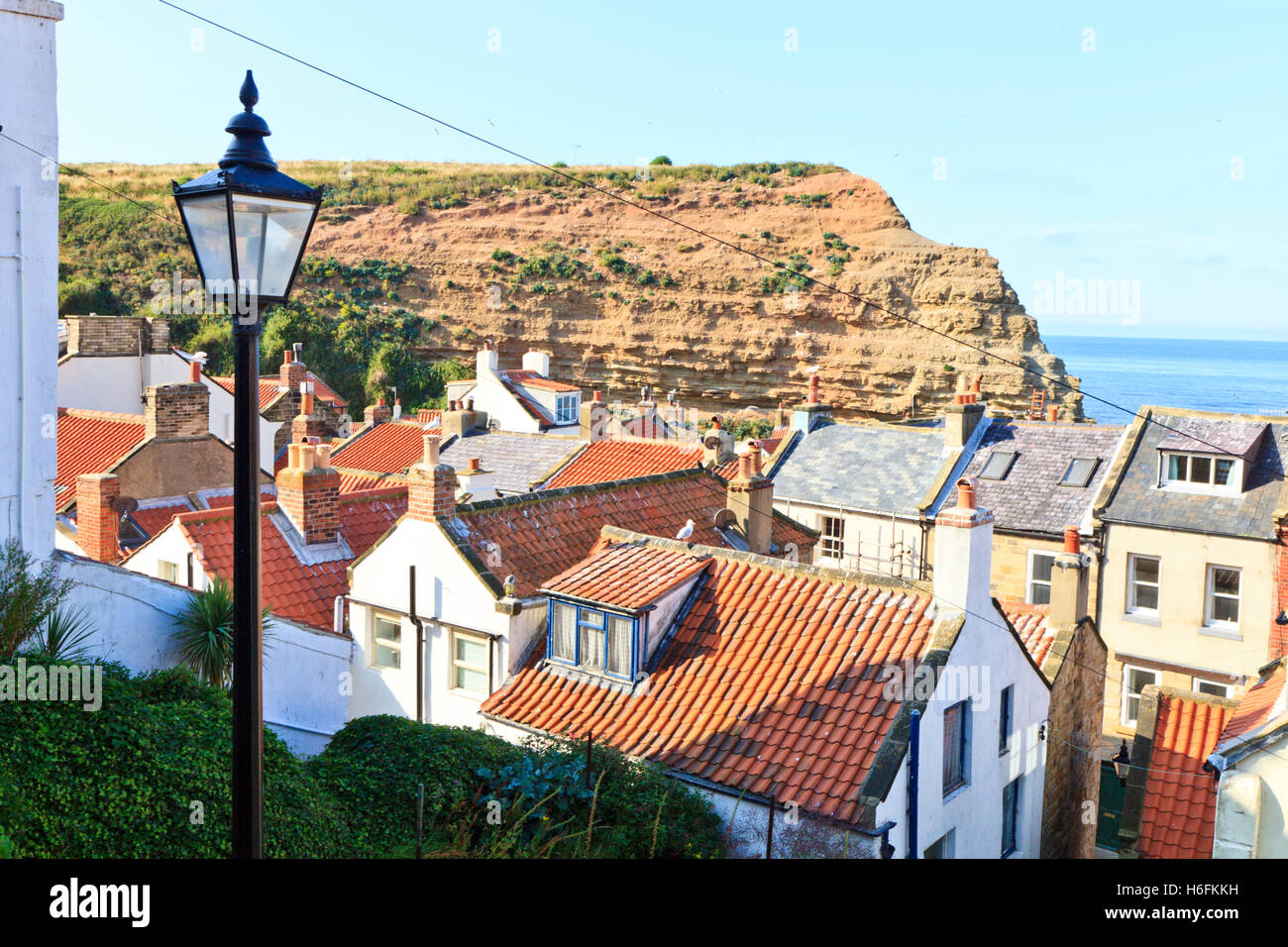 A tradional lamp post on a street above the red roofs of  Staithes Yorkshire Coast, England UK Stock Photo
