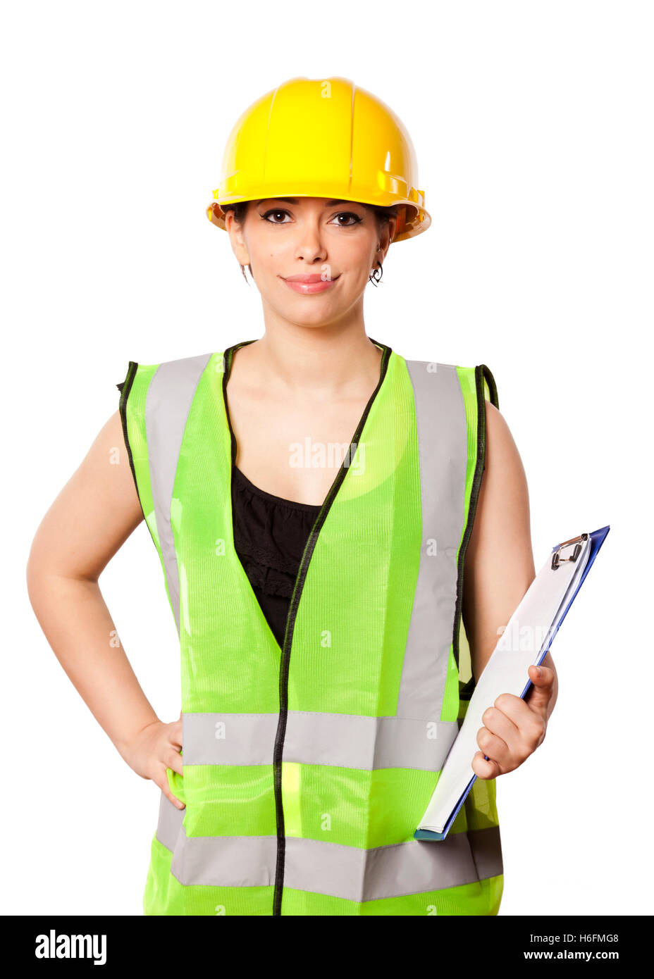 Caucasian young adult woman in her mid 20s wearing reflective yellow safety helmet and safety vest, giving the camera a smile wh Stock Photo