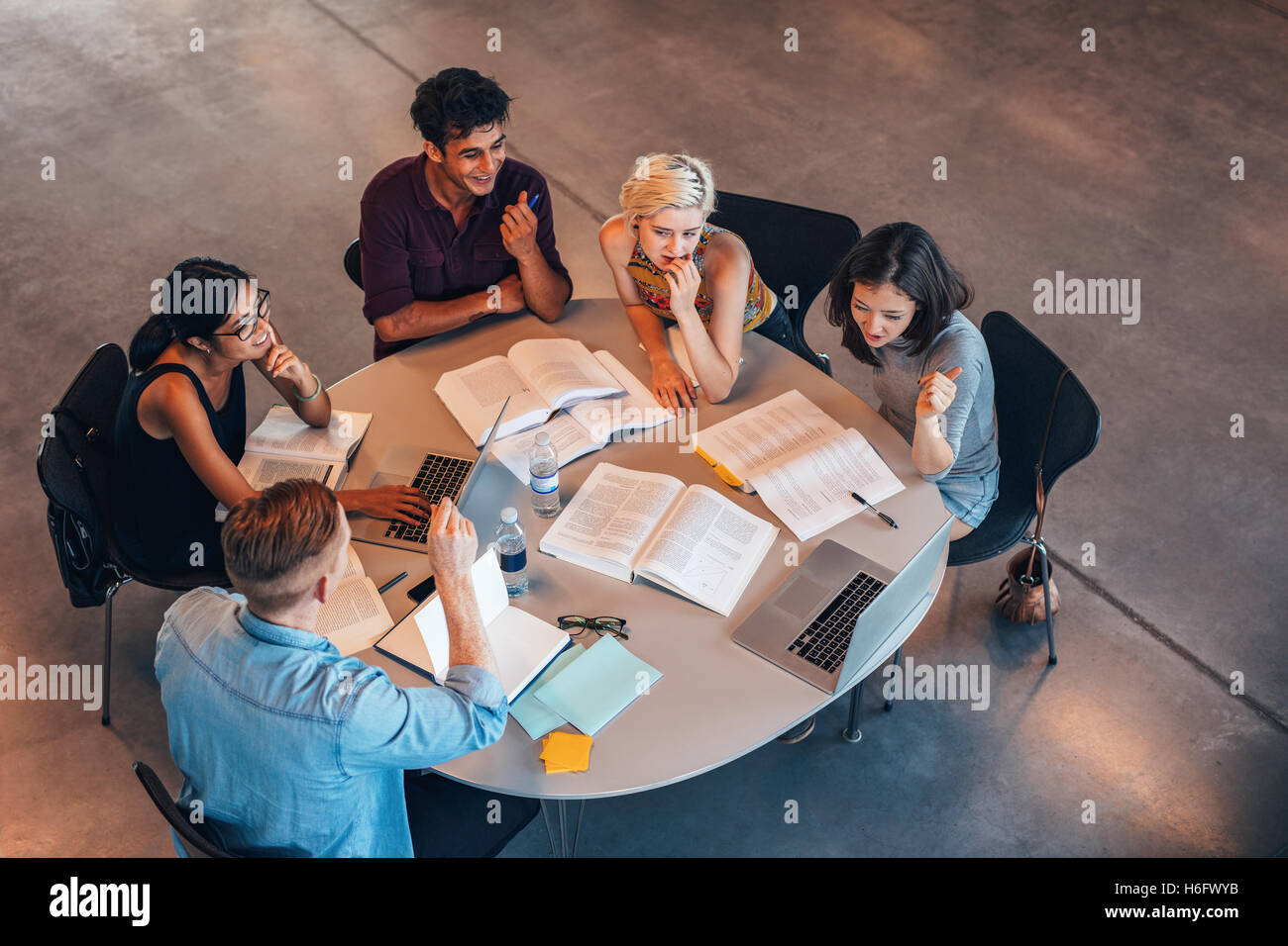 Group of young people studying together. Young students in cooperation with their academic assignment. Stock Photo