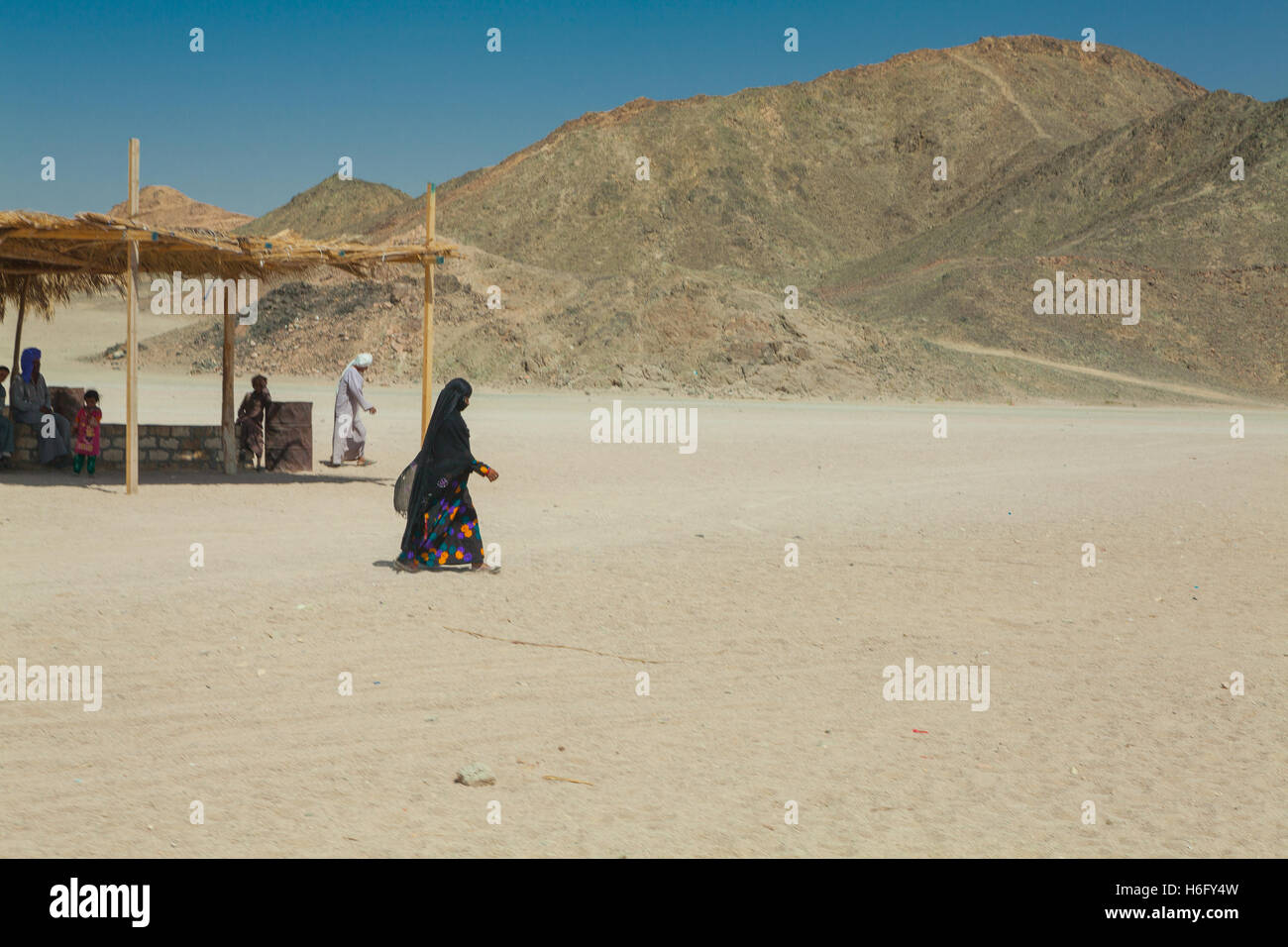 bedouin woman in black burqa walking in the desert Stock Photo