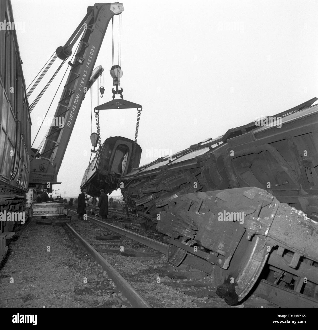A crane lifting one of the carriages as breakdown gangs worked at dawn to clear the blocked lines after the derailment late last night of the London to Edinburgh express train near the village of Conington, Huntingdonshire, England. Five people were killed and 18 injured in the crash. Stock Photo