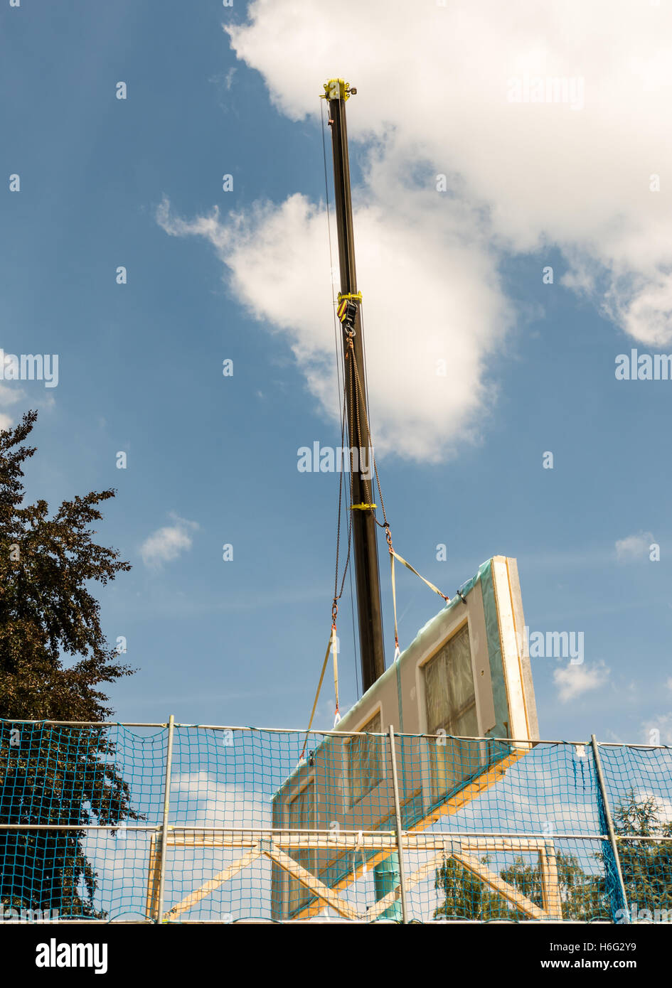 Assembling a prefabricated house - wall is hanging on a crane Stock Photo