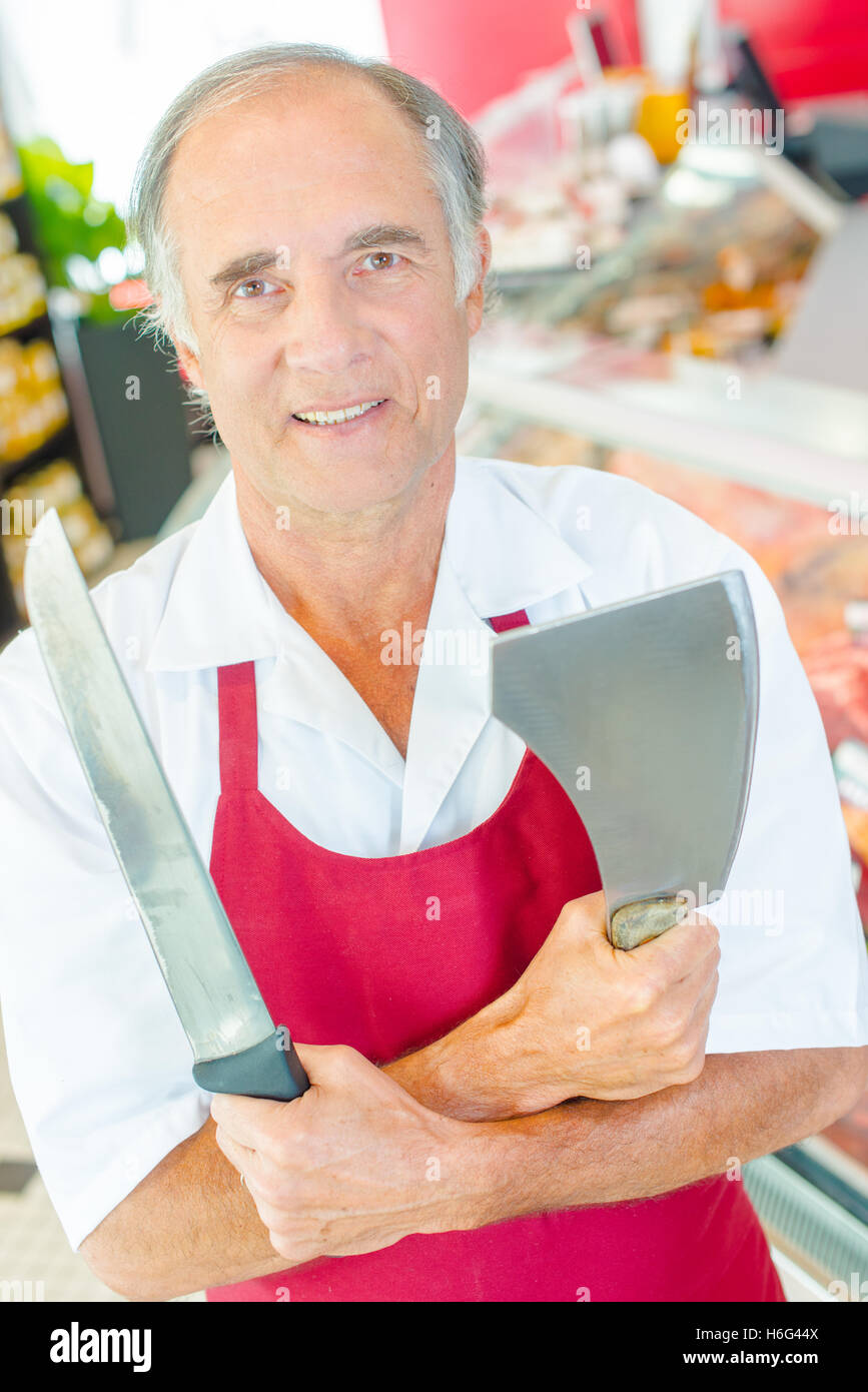 Butcher holding knife and cleaver, arms crossed Stock Photo Alamy