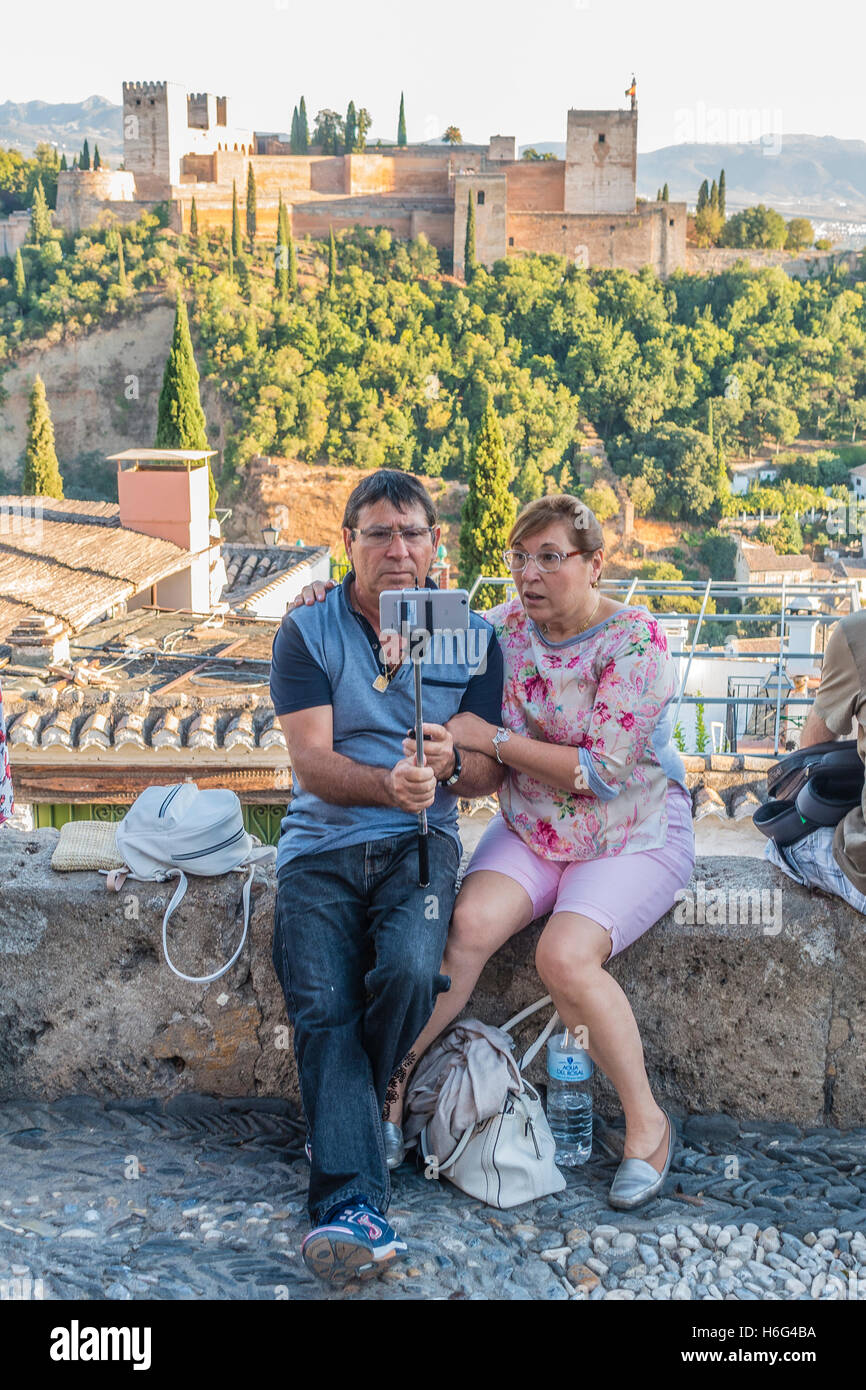 A middle-age tourist couple inspect a selfie they have just taken using a selfie-stick at the Mirador de San Nicolas. Stock Photo