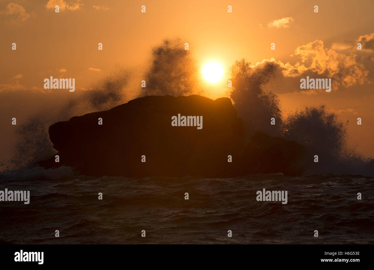 Dawn waves break over a large rock in Old Town Bay, St Mary's. Isles of Scilly Stock Photo
