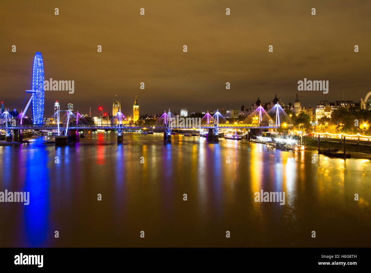 A nighttime photo taken from Waterloo Bridge looking along the River Thames towards the London Eye and Big Ben. Stock Photo