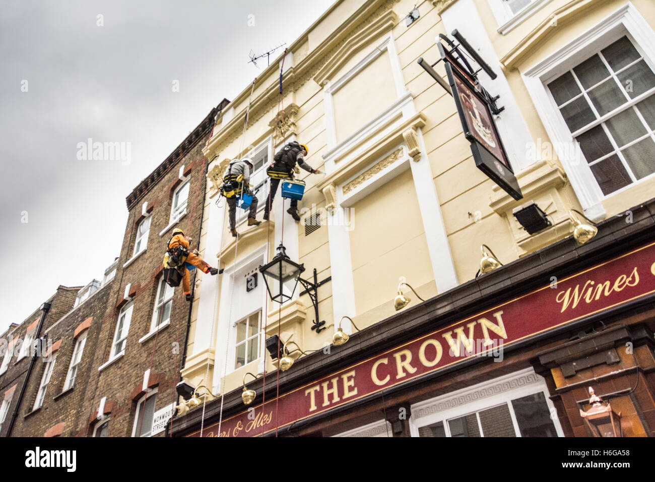 Painters and decorators abseiling the exterior of the Crown public house on Monmouth Street, London, WC2 Stock Photo