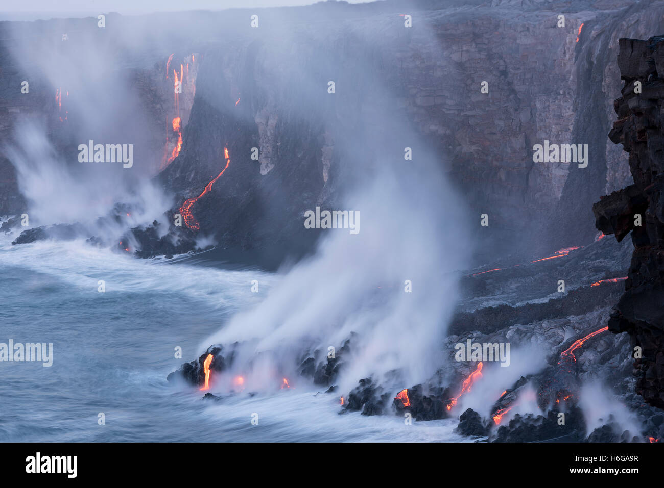 hot lava from Kilauea Volcano, flows over sea cliffs and through lava tubes into the ocean, Hawaii Volcanoes National Park, USA Stock Photo