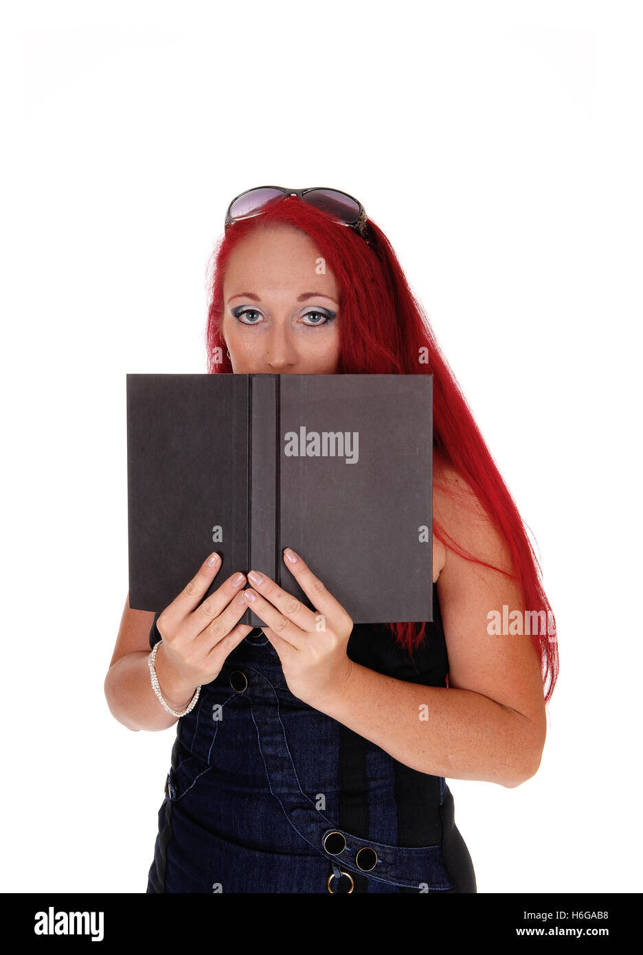 A business woman holding a book on her face, standing with long red hair isolated for white background. Stock Photo