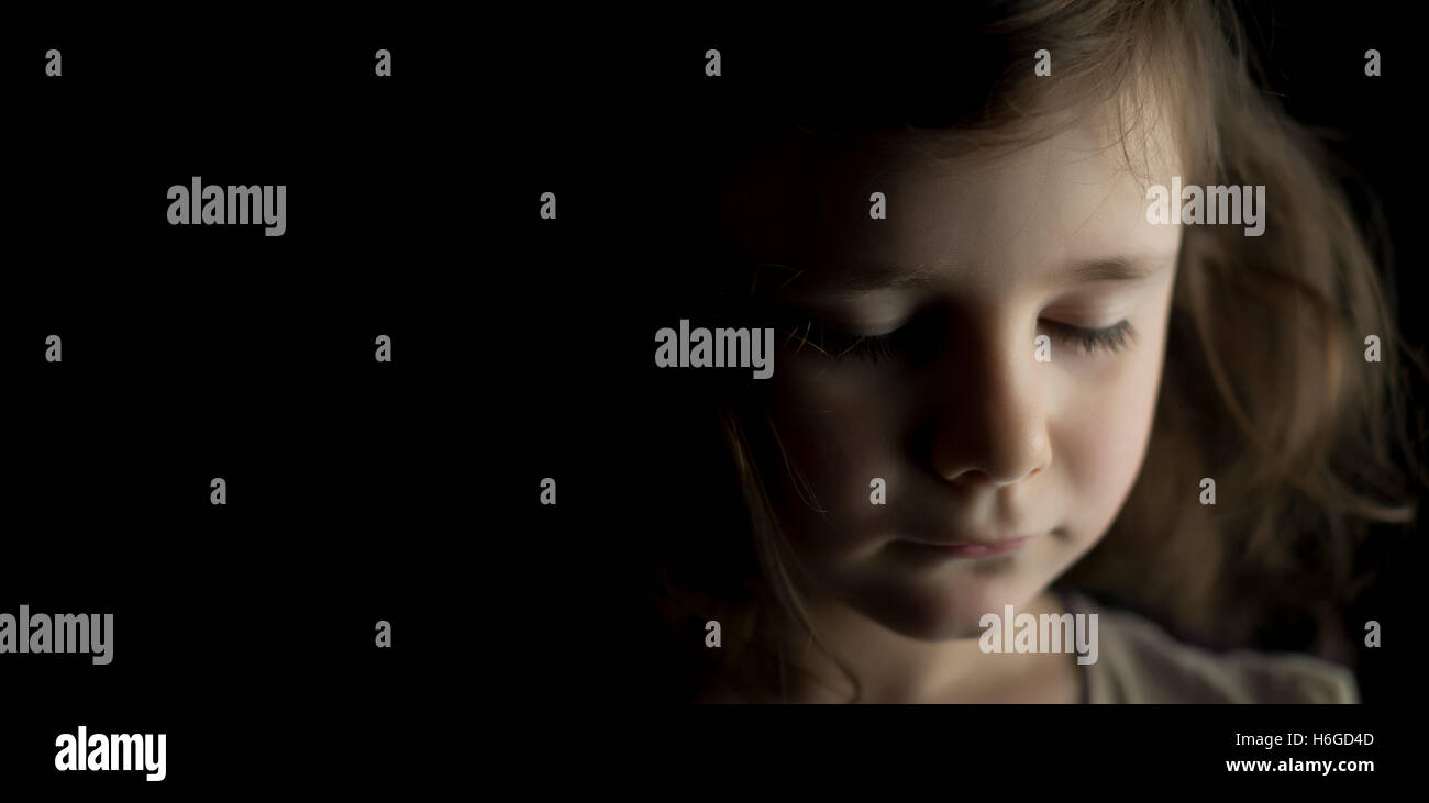 Portrait of young girl in studio on black background with copy space ...