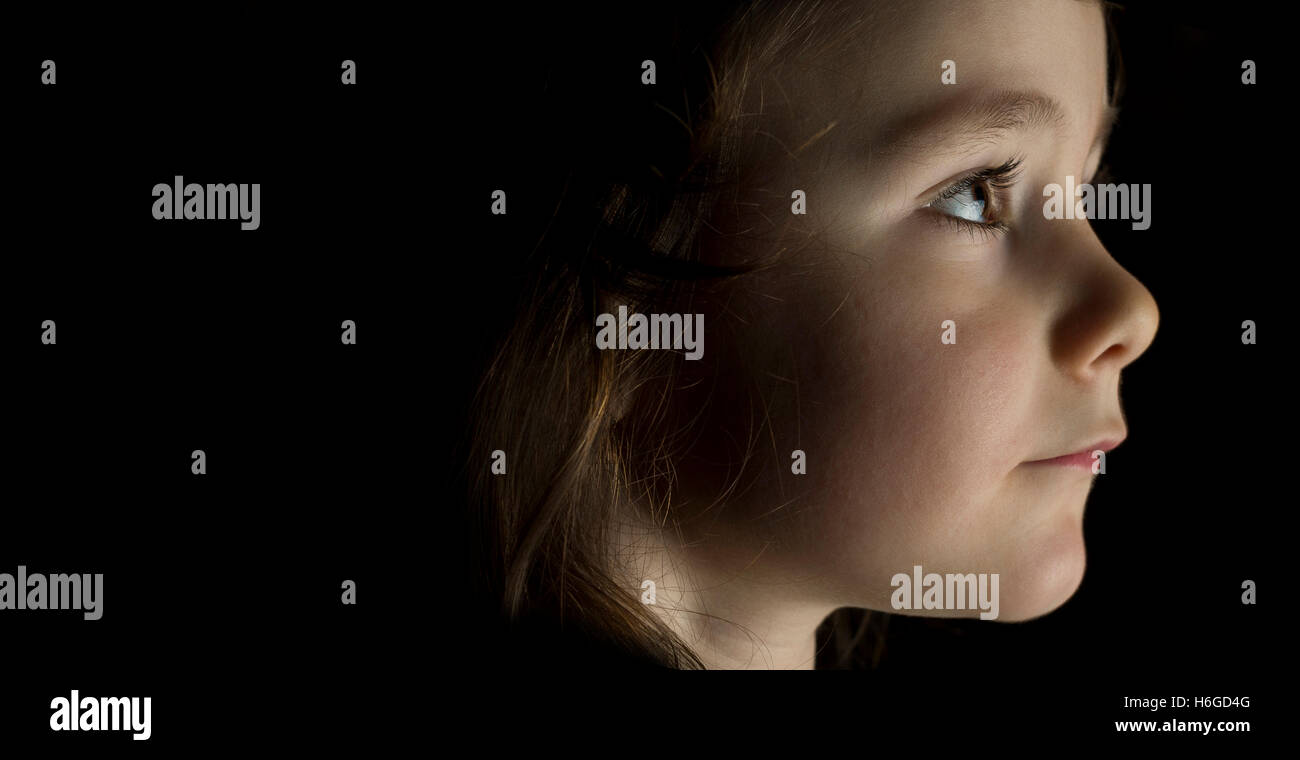 Portrait of young girl in studio on black background with copy space ...