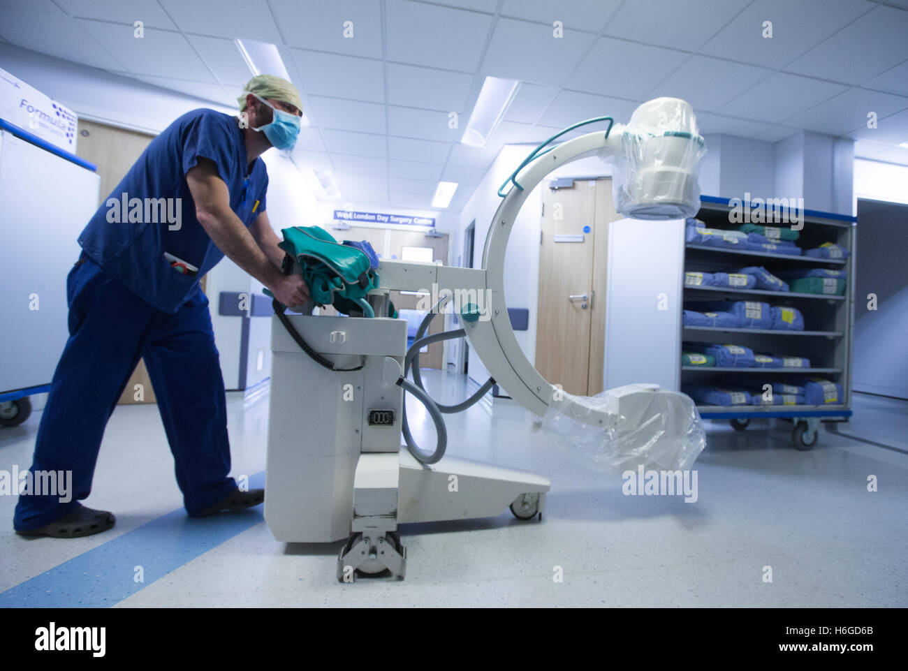 A hospital technician pushes an X Ray machine along a corridor Stock