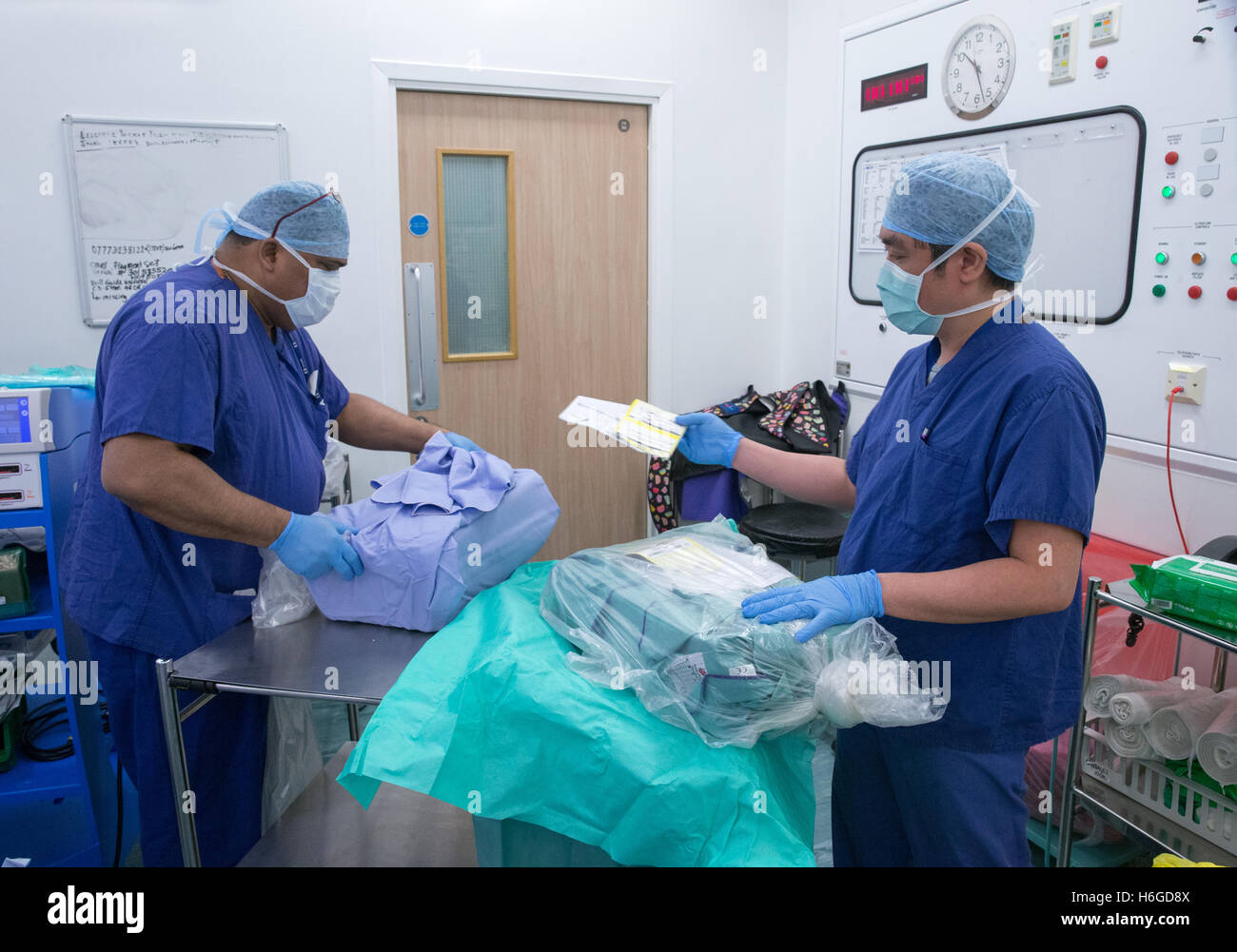 Medical staff in a hospital operating theatre during an operation opening the sterile packs for knee replacement surgery Stock Photo