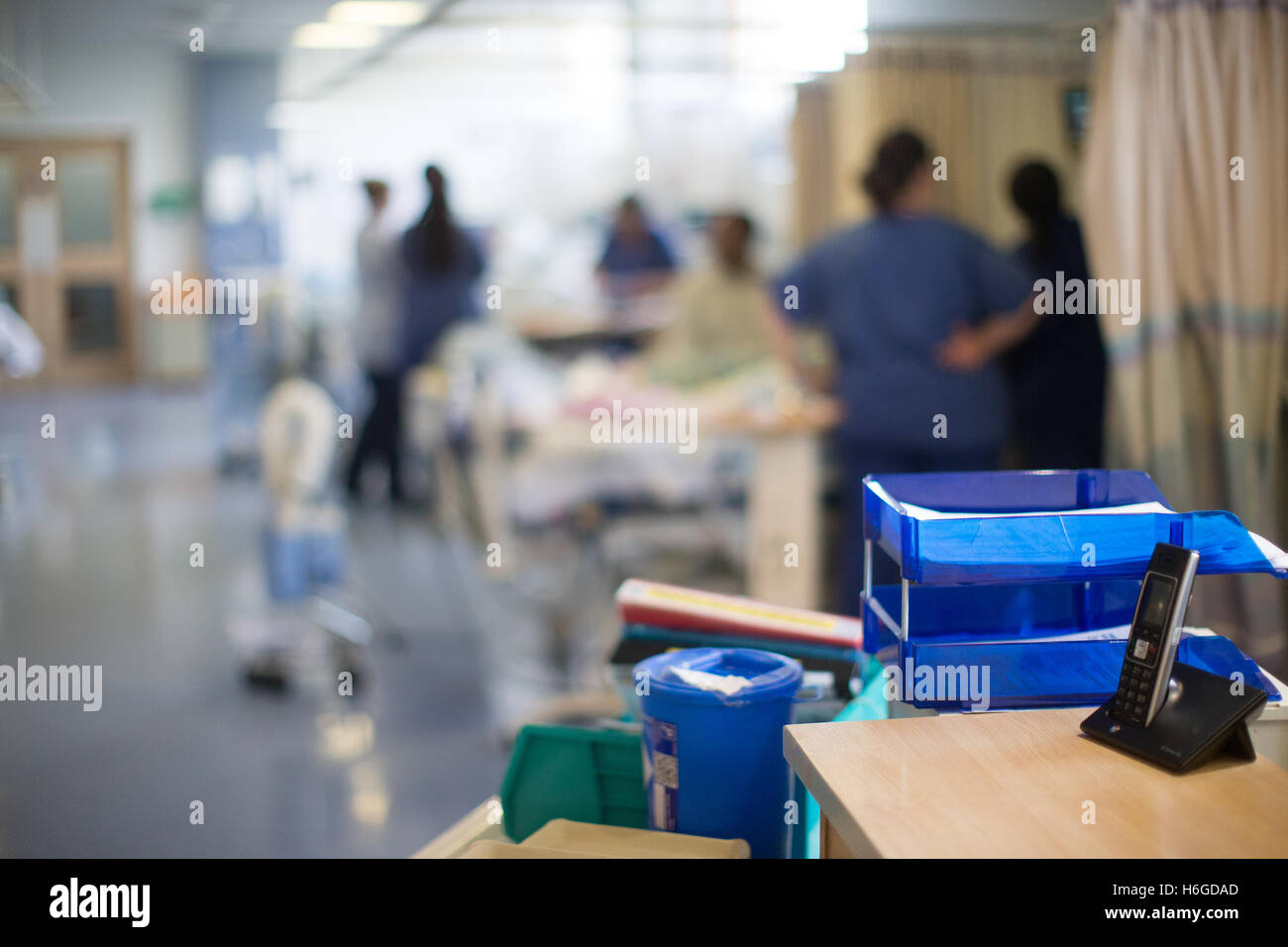 Photo of workstation in a hospital ward with patients and staff in the background Stock Photo