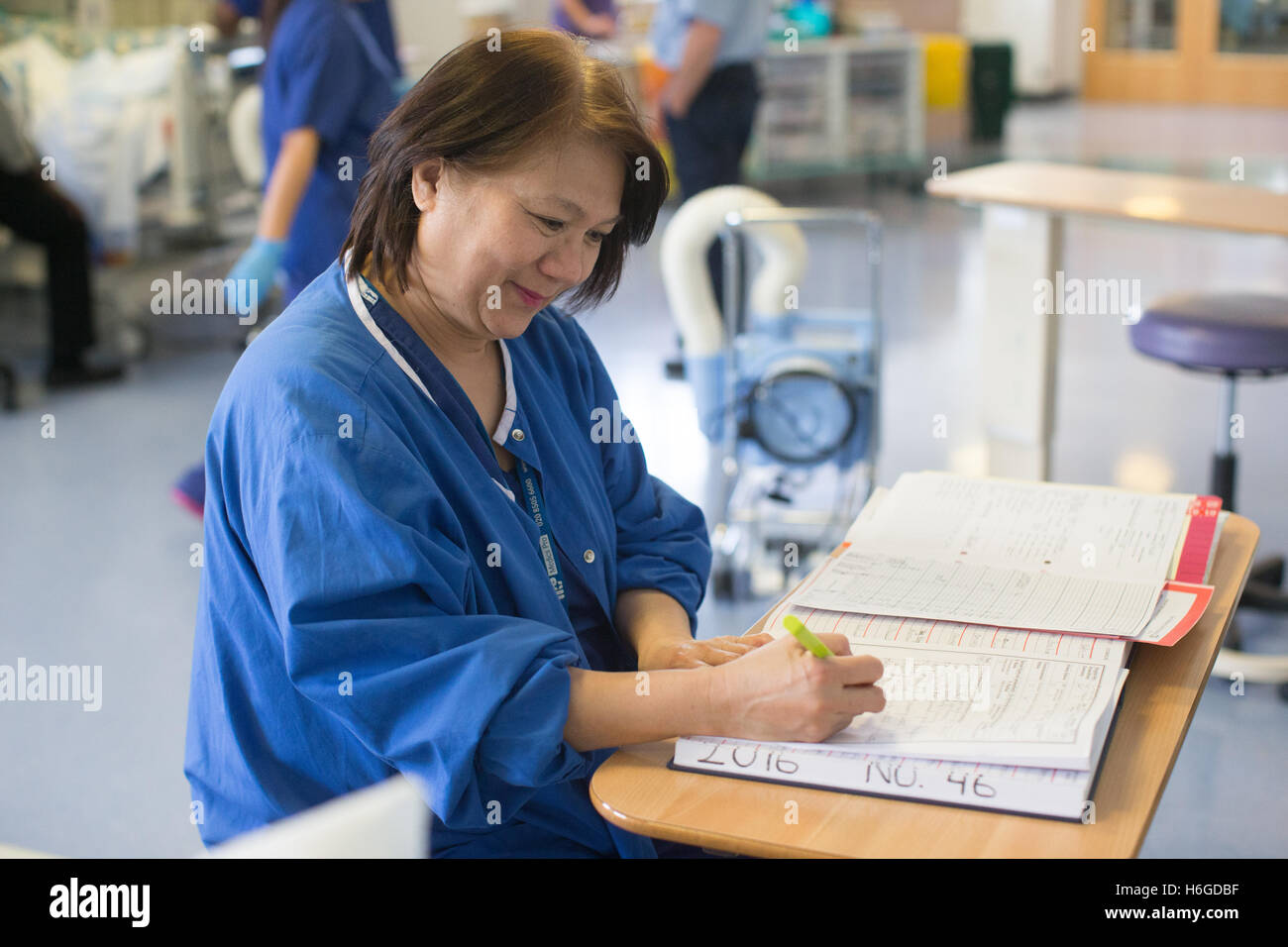 A nurse in a hospital ward makes notes in the patients logbook Stock Photo