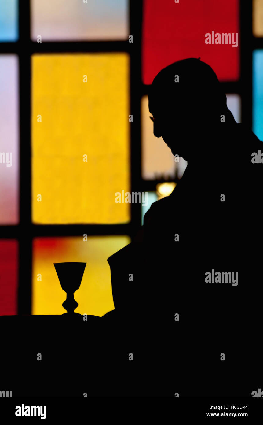 priest in silhouette, unrecognizable,  during The Eucharist of a Catholic mass Stock Photo