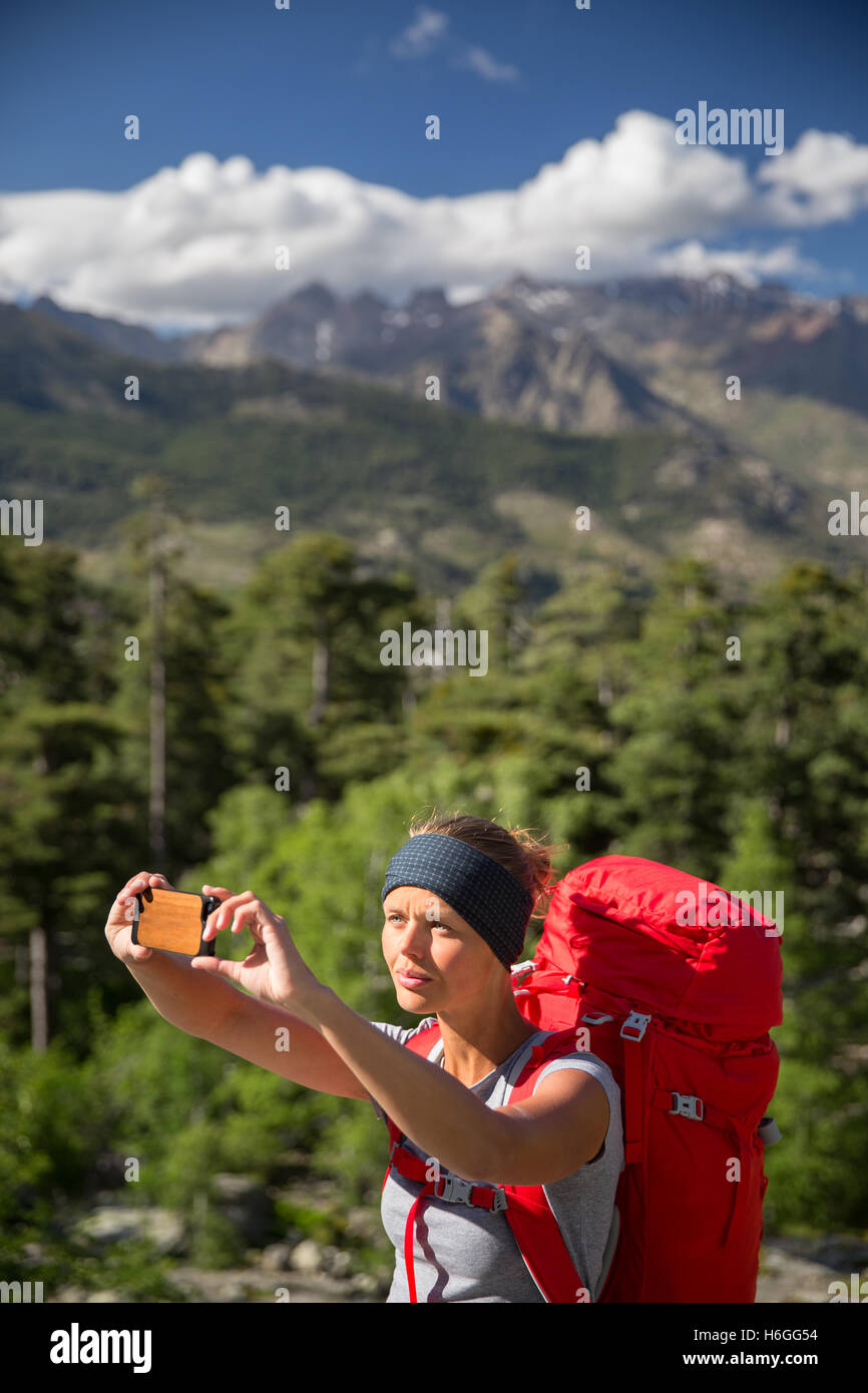 Pretty, young woman hiker taking a selfie photo with her smart phone in ...