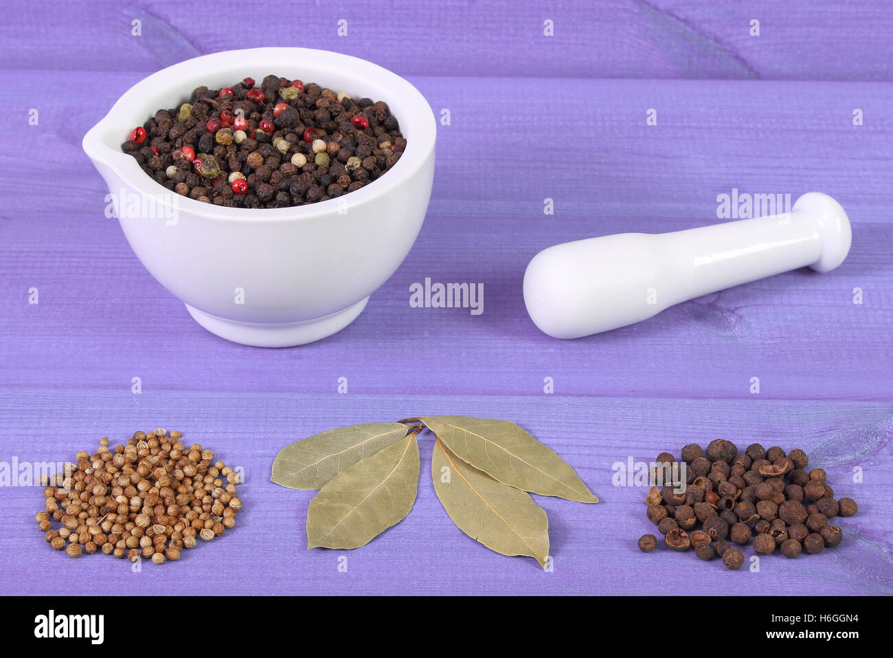 Colorful pepper in white glass mortar and spices on purple boards, seasoning for cooking Stock Photo