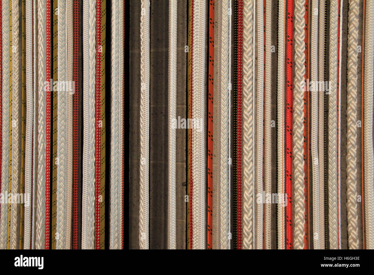 Horizontal image of vertical lines in thick and thin braided ropes that are coarse in texture and make a unique background. Stock Photo