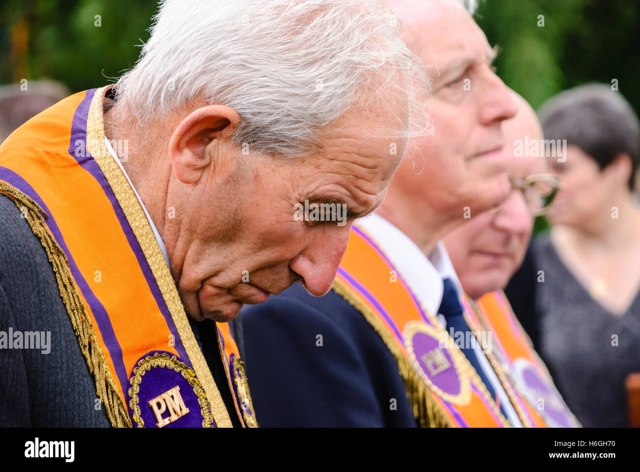 Orangeman wearing an orange sash collarette prays during an outdoor service in 'The Field' on the 12th July. Stock Photo