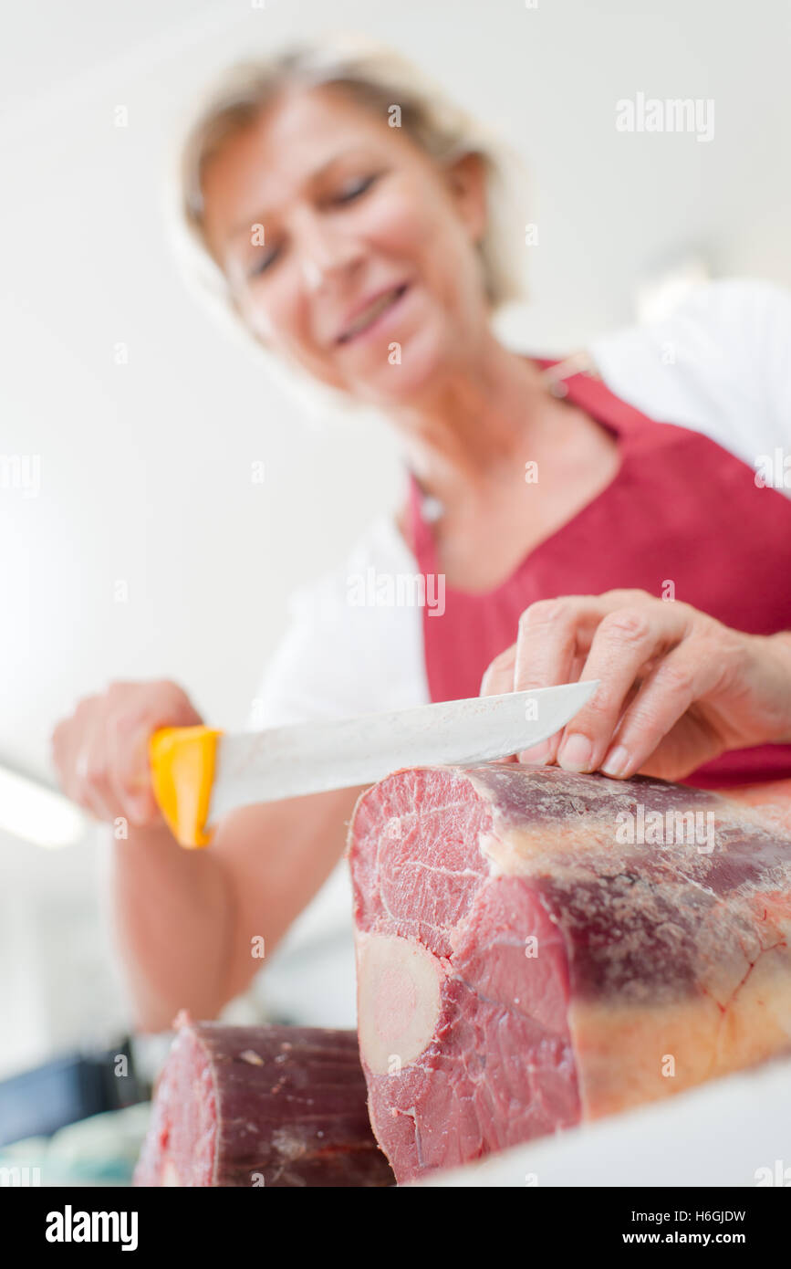 Female butcher slicing beef Stock Photo