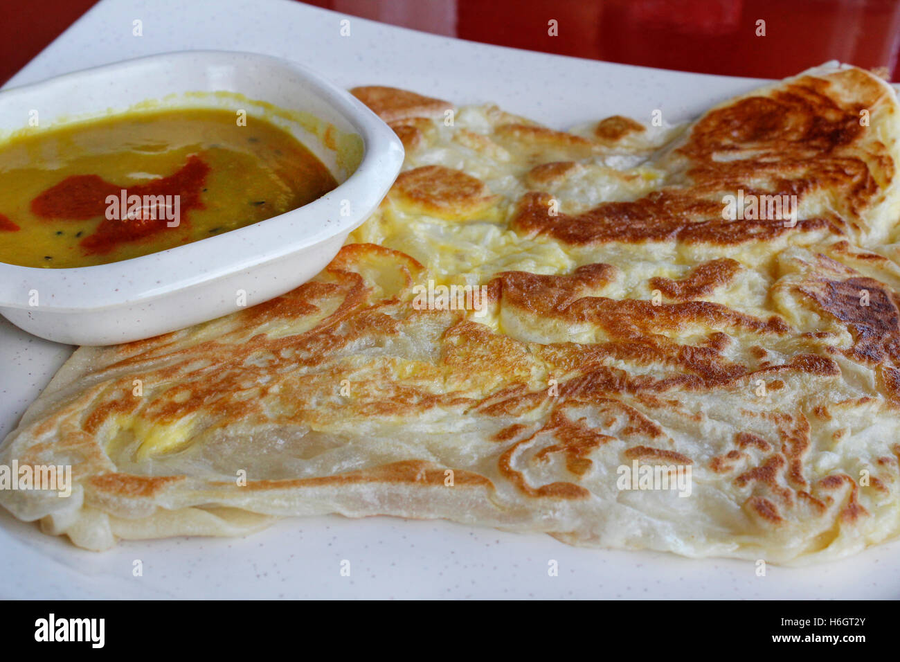 Plain roti canai or pan fried flatbread consisting of dough, egg, ghee and serve with the curry sauce Stock Photo