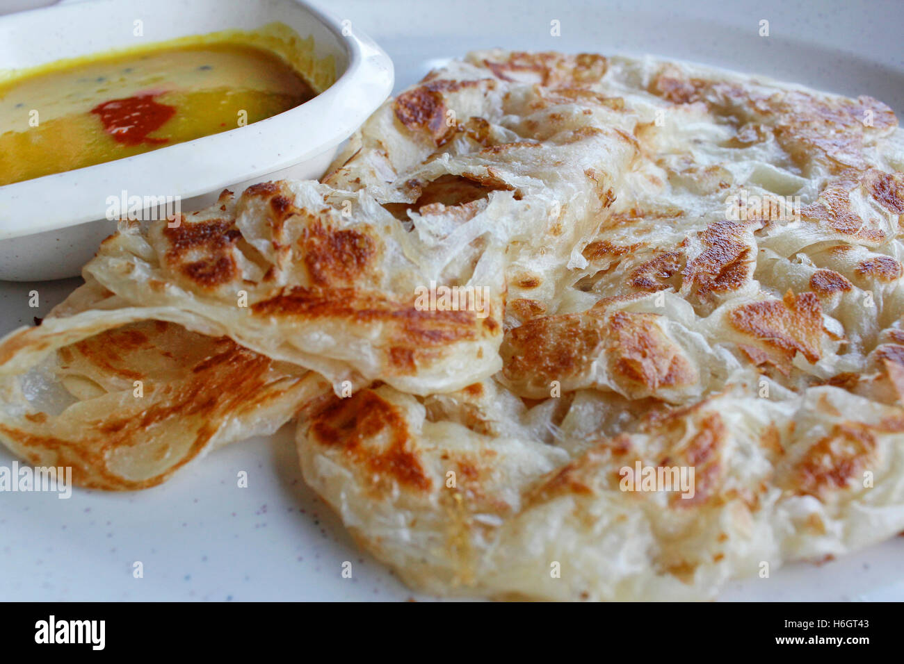 Plain roti canai or pan fried flatbread consisting of dough, egg, ghee and serve with the curry sauce Stock Photo