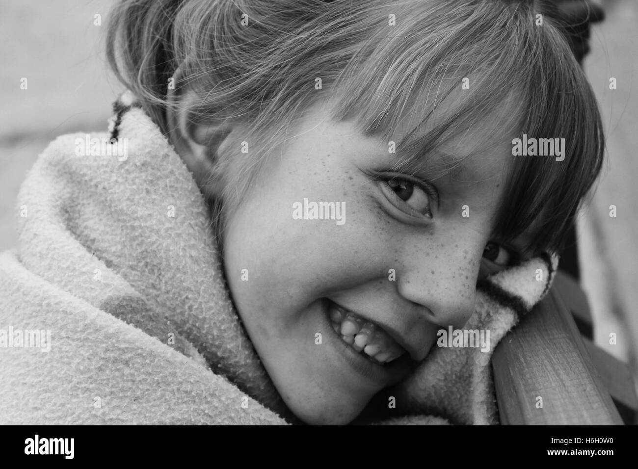 black and white portrait of little girl wrapped in blanket smiling at the camera with teeth showing Stock Photo