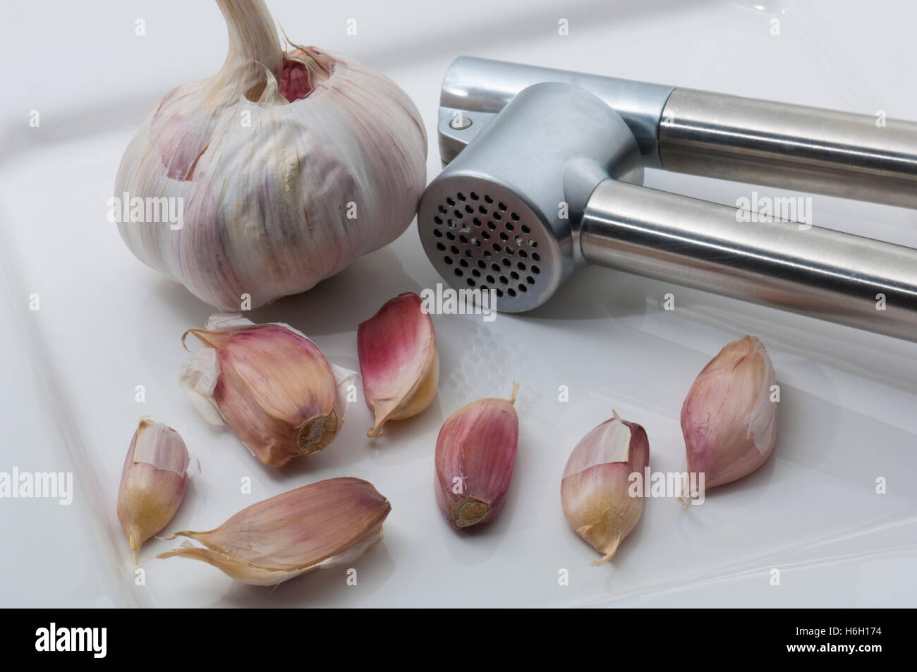 Garlic with a garlic press on a plate Stock Photo