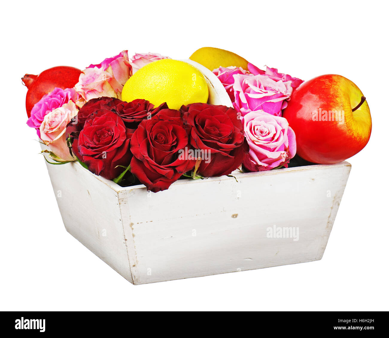 Flower arrangement of red roses and fruits in wooden basket isolated on