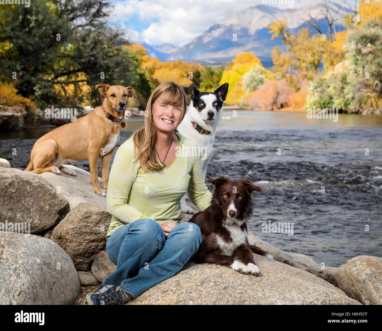 Outdoor portrait of attractive woman with her three dogs alongside the Arkansas River; Salida; Colorado; USA Stock Photo