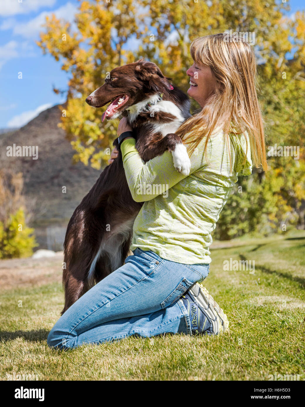 Attractive woman playing with her border collie dog on a grassy field Stock Photo