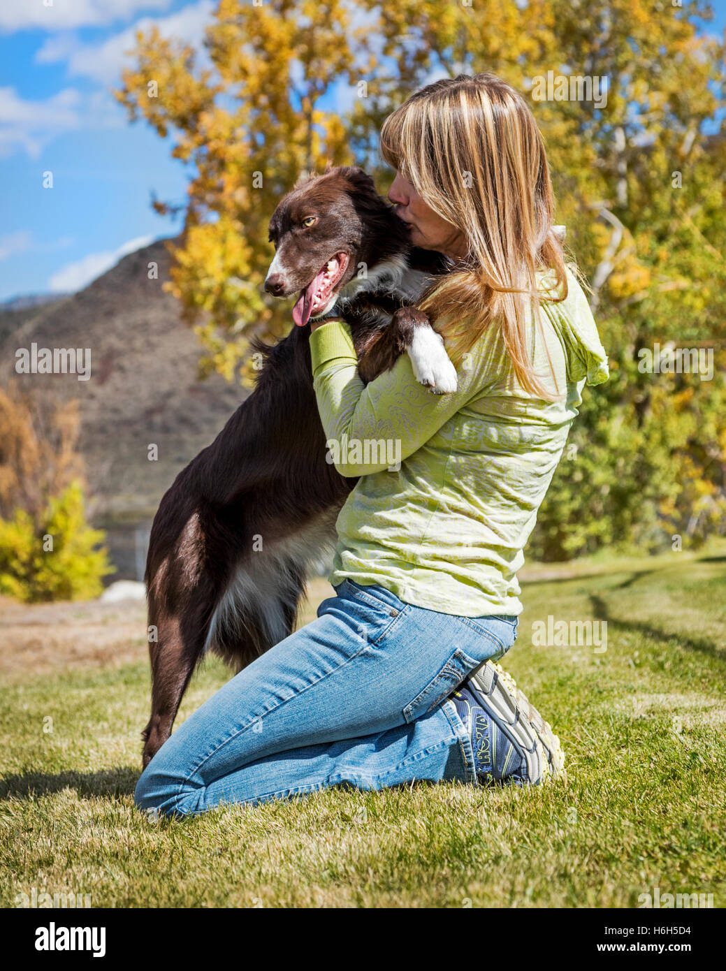 Attractive woman playing with her border collie dog on a grassy field Stock Photo
