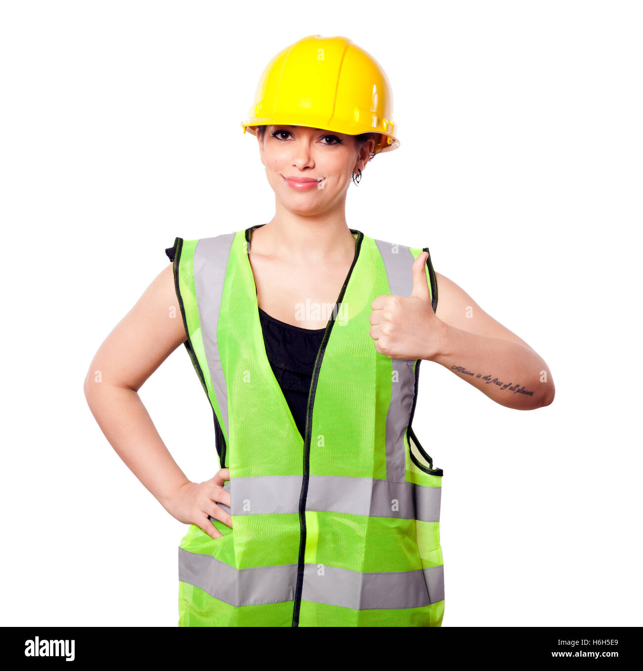 Caucasian young adult woman in her mid 20s wearing reflective yellow safety helmet and safety vest' giving the camera the thumbs Stock Photo