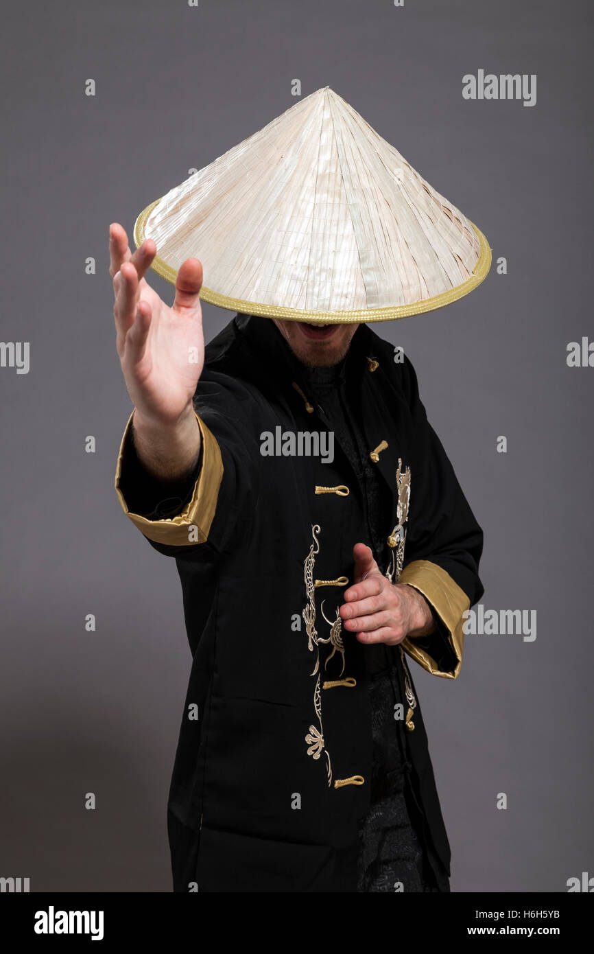 Studio shot of a man in his late twenties, wearing traditional chinese clothing and Kung-Fu posture; identity hidden. Stock Photo