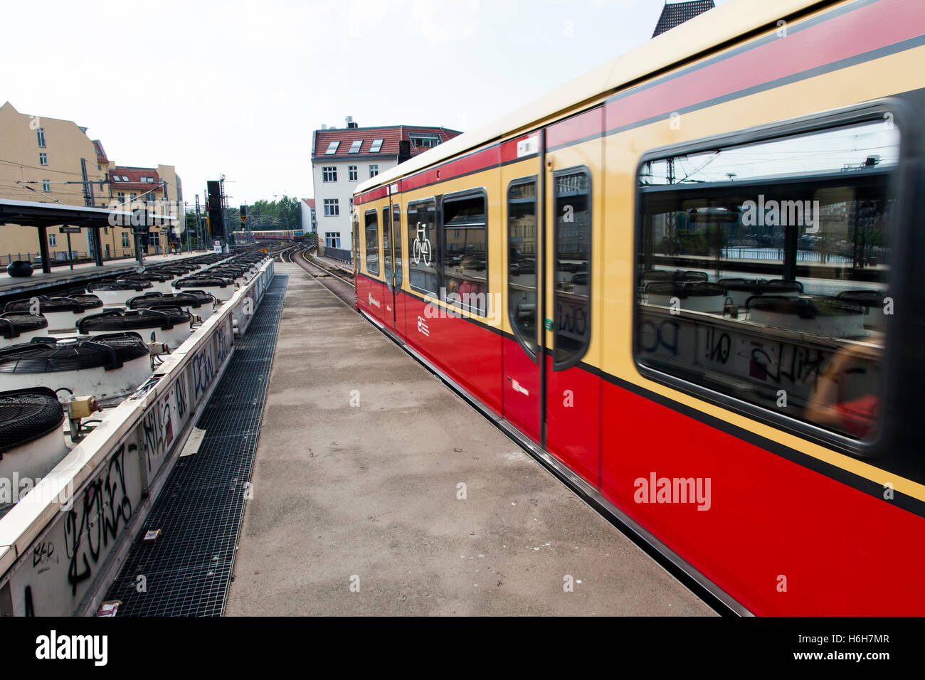 Train leaving an urban railway station platform in Berlin, with a long row of ventilators that circulate the air for the undergr Stock Photo