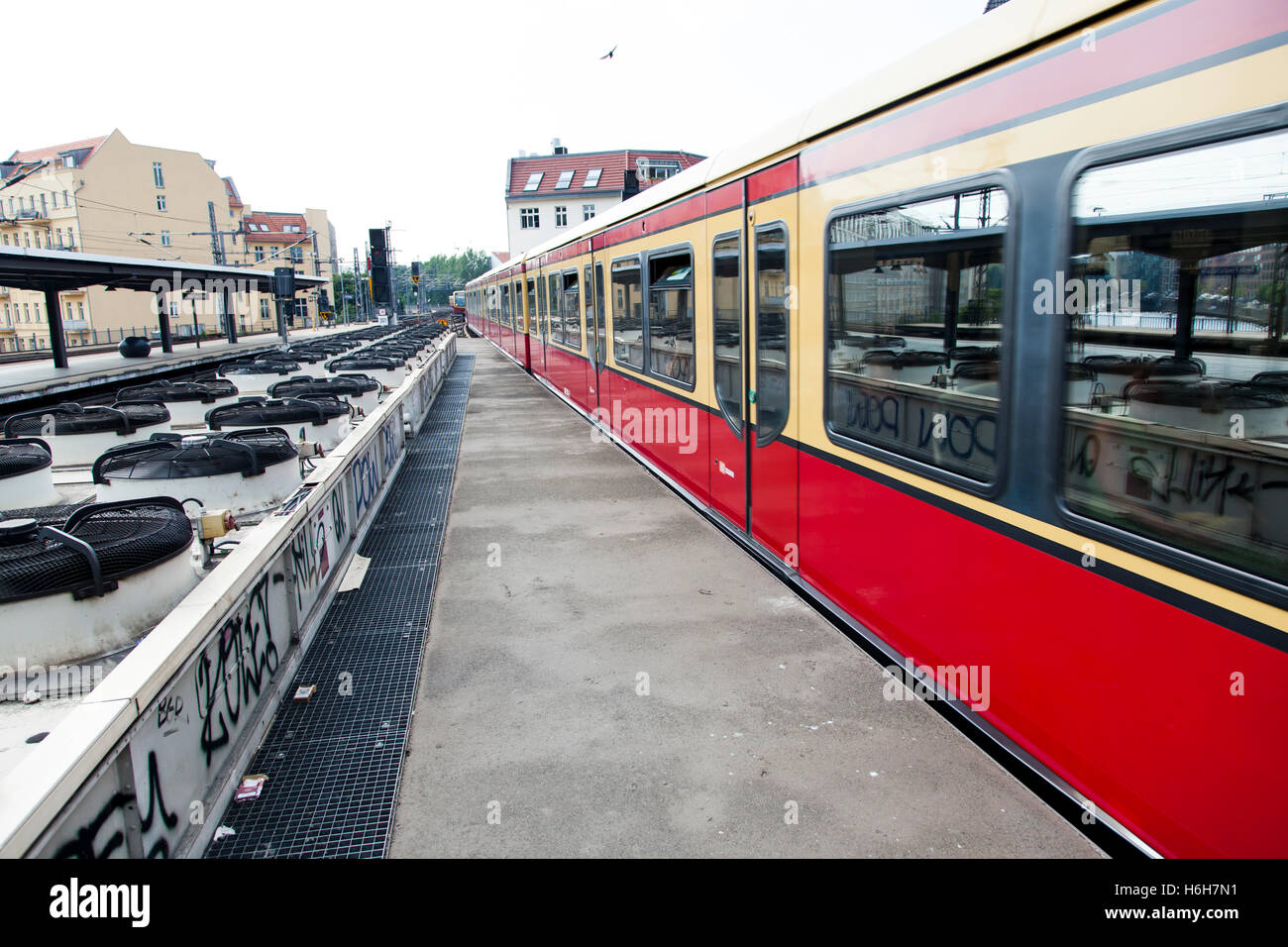 Train leaving an urban railway station platform in Berlin, with a long row of ventilators that circulate the air for the undergr Stock Photo