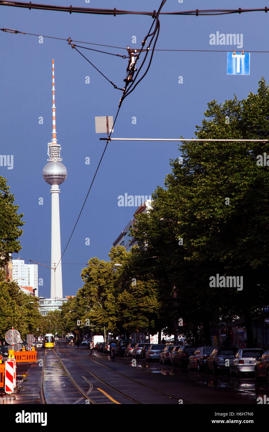 A yellow tram riding on a Berlin street with the famous Fernsehturm in the background. Stock Photo