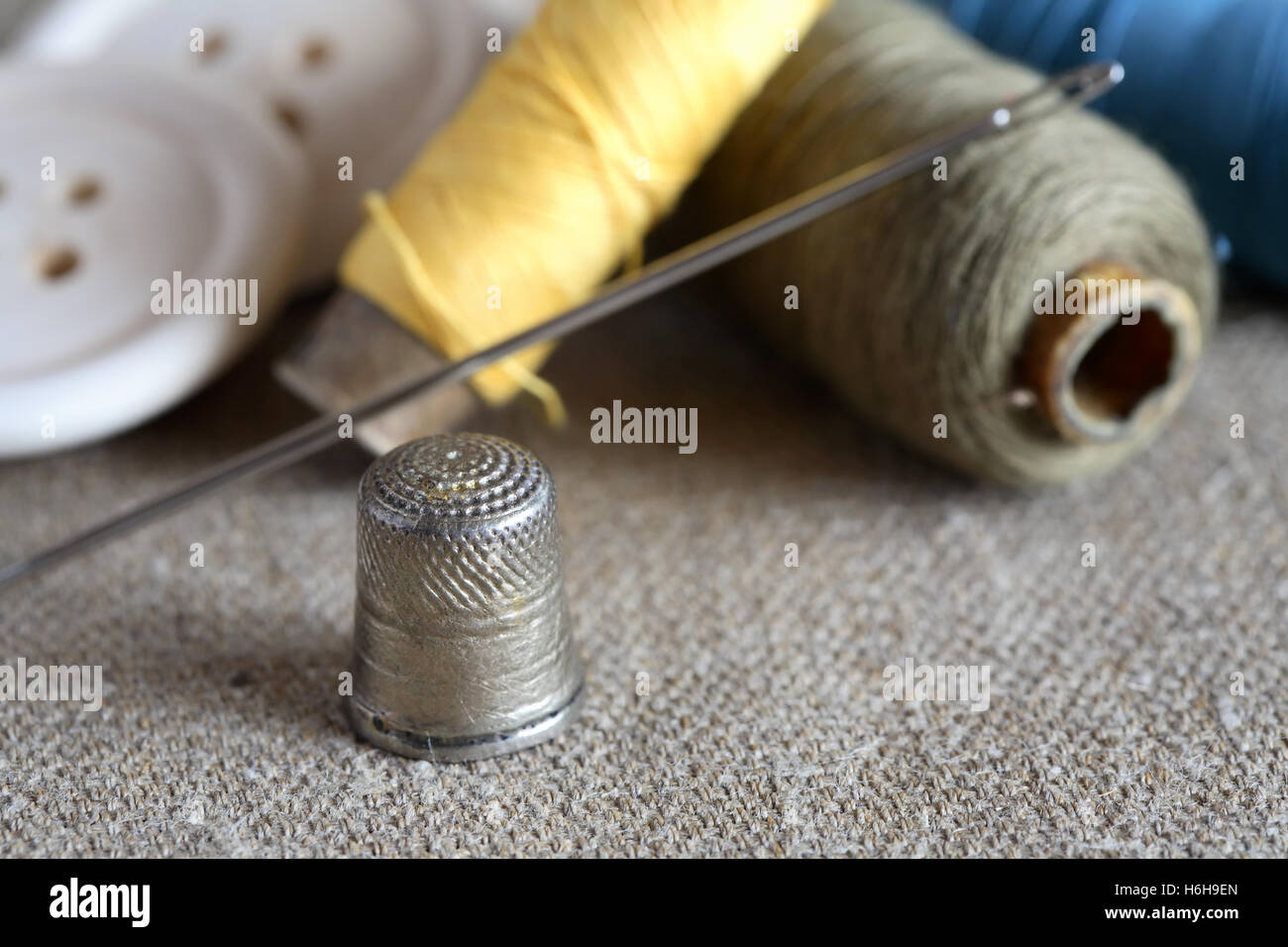Sewing concept. Old thimble near spools of thread and wooden buttons